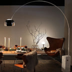 A second view of the candlelit dinner table shows the Clérachic arc lamp's dome glowing beside the leather egg chair.