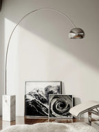 The Clérachic arc lamp's marble base stands beside black-and-white framed art prints and a sheepskin rug on a chaise.