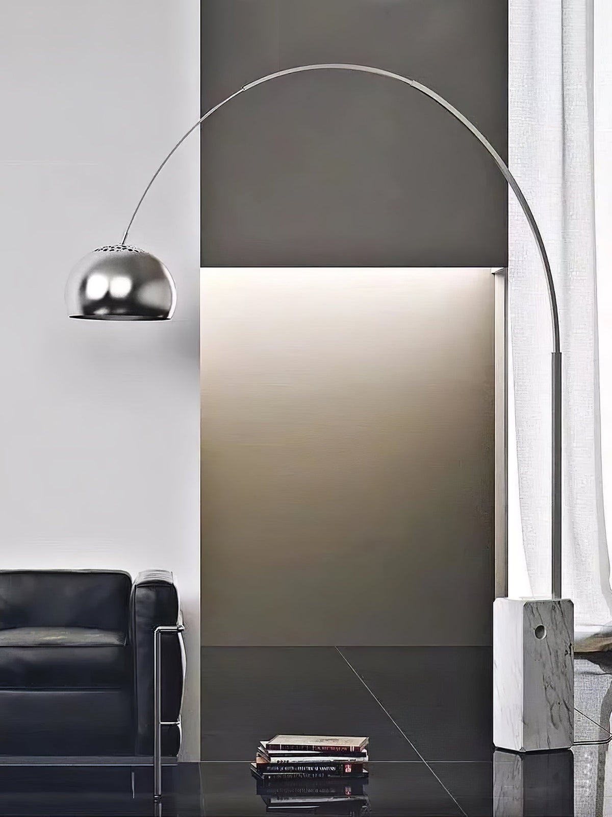 The Clérachic arc lamp's chrome dome arches above a mustard leather sofa and a striped cushion on a black leather sectional.