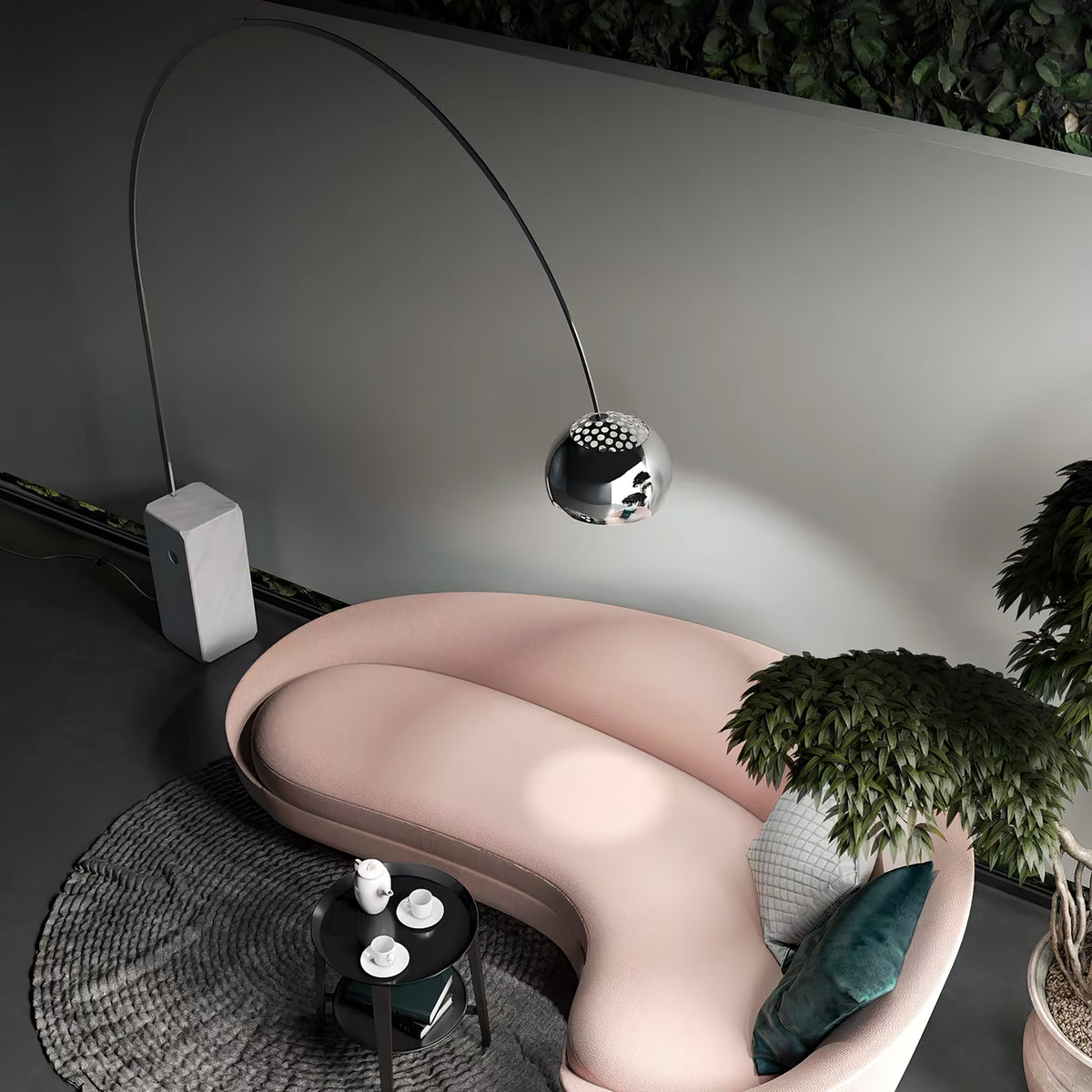 Seen from above, the Clérachic lamp's dimpled chrome dome hovers over a curved blush sofa beside a leafy indoor plant.