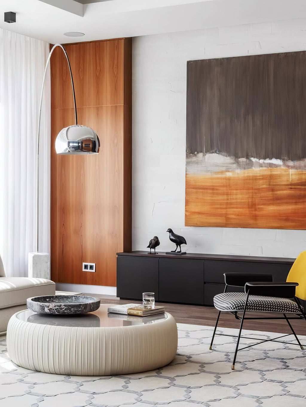 The Clérachic arc lamp's chrome dome curves past a walnut panel wall, its marble base near a black sideboard with bird figures.