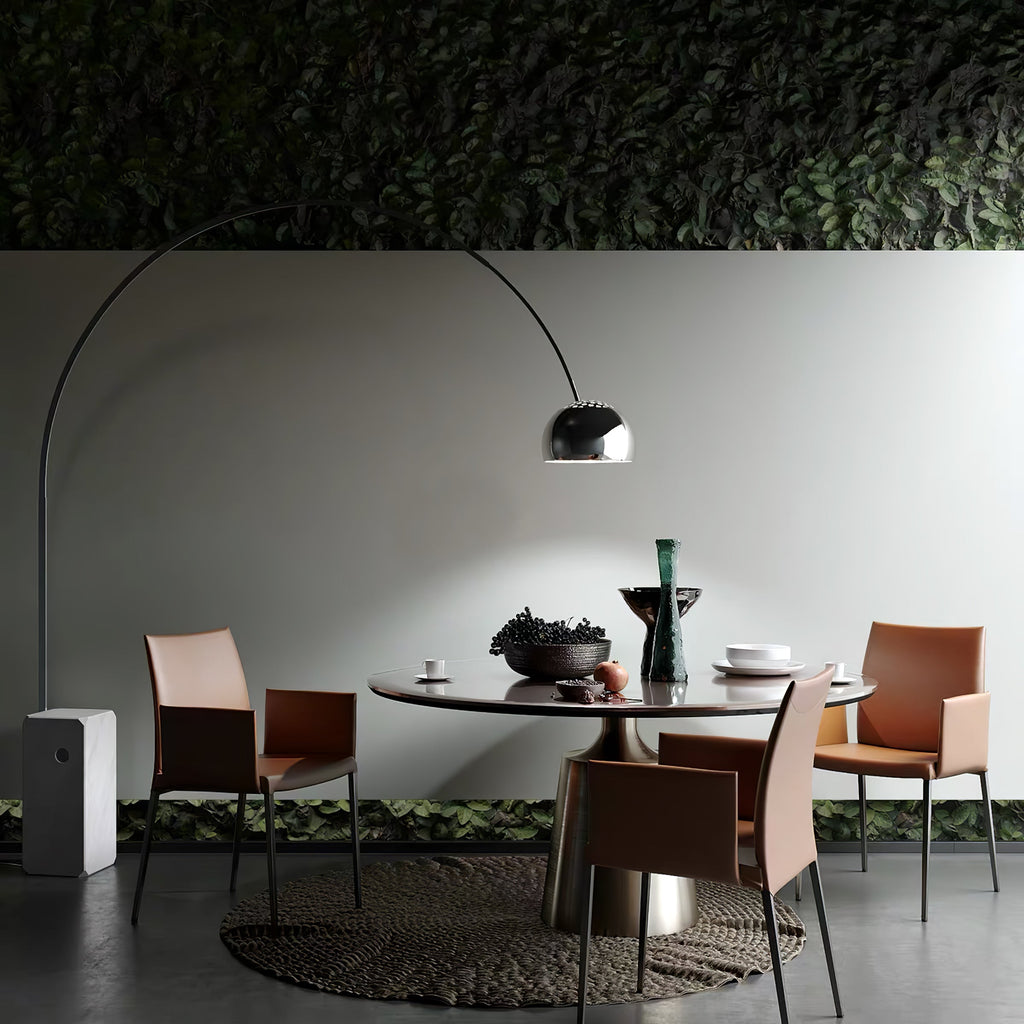Beneath a living green wall, the Clérachic arc lamp's dome hangs above a dark oval table set with pink leather chairs.