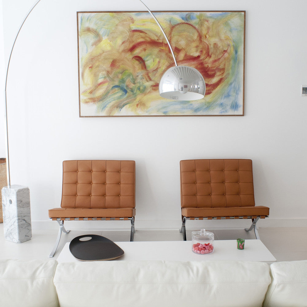 The Clérachic lamp's chrome dome is set against a large abstract painting, its marble base beside two tan leather Barcelona chairs.
