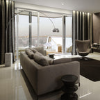 At dusk, the Clérachic arc lamp's chrome dome glows softly over a grey sofa in a high-rise flat with a city skyline behind it.