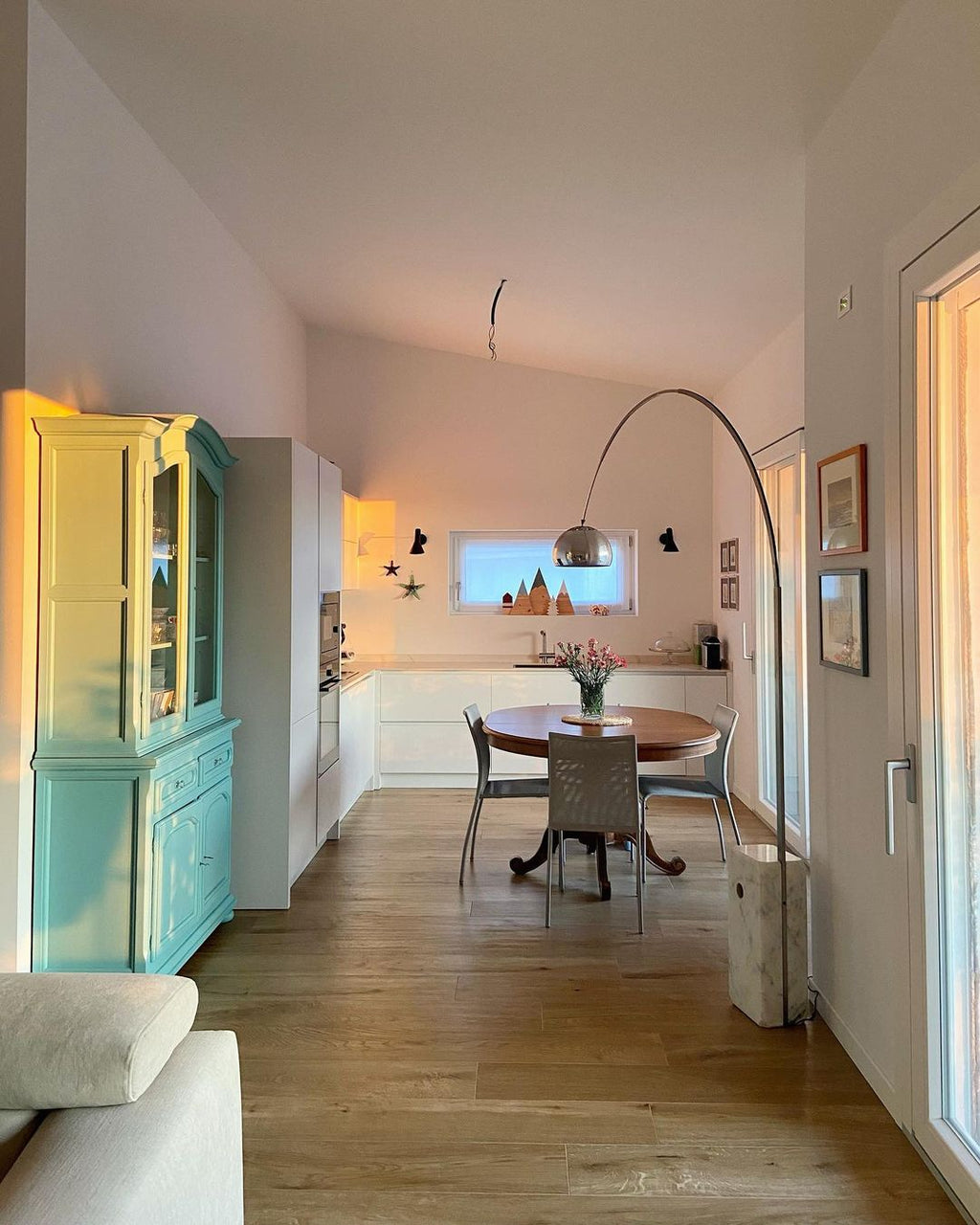 In a kitchen-diner with a mint vintage cabinet, the Clérachic lamp's marble base stands beside a round wooden dining table.