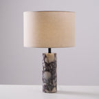 Purple veining shows clearly in the column base of the Clérachic marble lamp, set on a plain grey studio background.