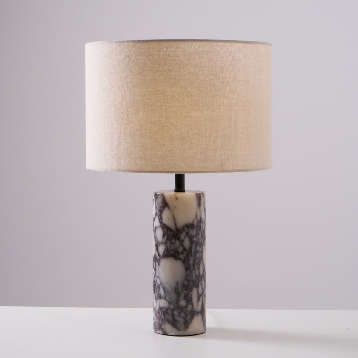 Purple veining shows clearly in the column base of the Clérachic marble lamp, set on a plain grey studio background.