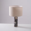 Clérachic marble table lamp photographed straight-on against a plain grey studio background, shade lit from within.