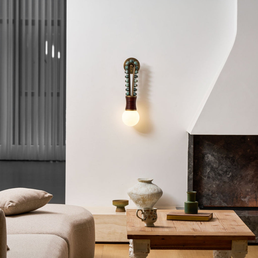 Clérachic wall sconce lit beside a fireplace in a modern living room, with a sofa and coffee table nearby.