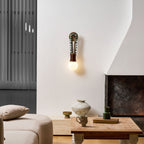 Clérachic wall sconce lit beside a fireplace in a modern living room, with a sofa and coffee table nearby.