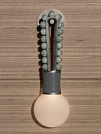 Sage-green beads glow above a grey-wrapped base on a Clérachic wall sconce mounted to a wood-plank wall.