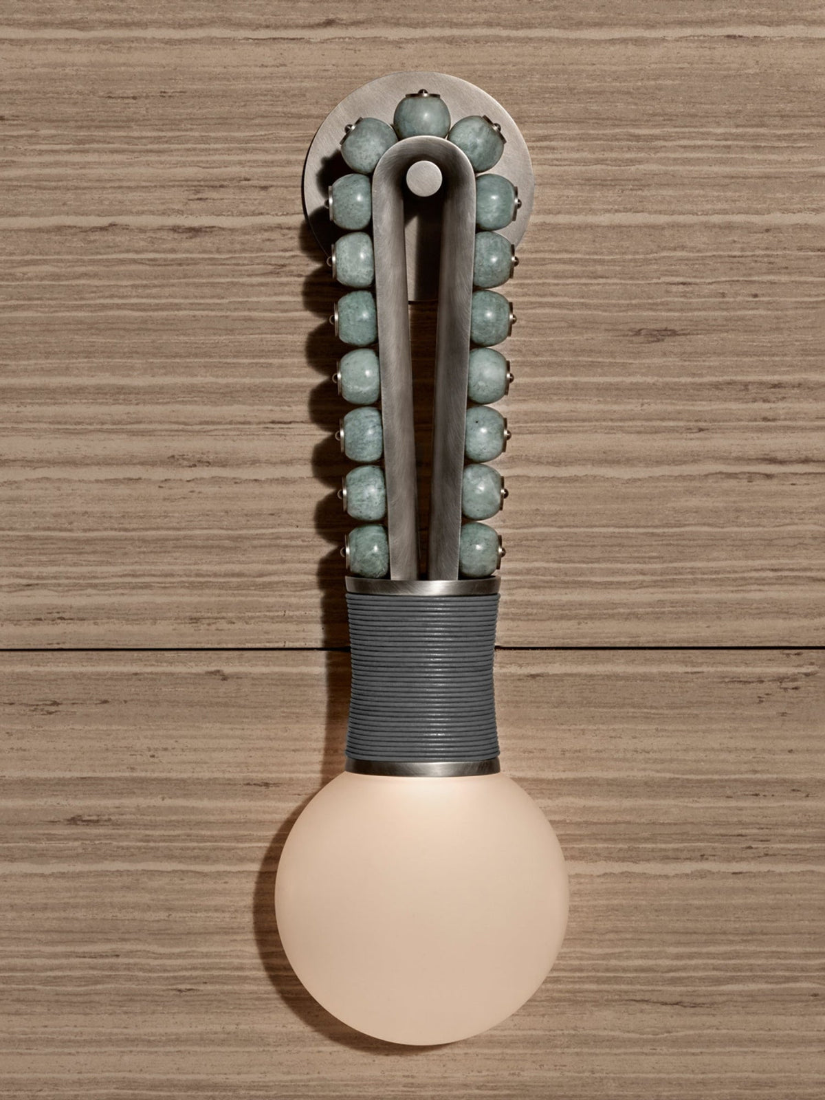 Sage-green beads glow above a grey-wrapped base on a Clérachic wall sconce mounted to a wood-plank wall.