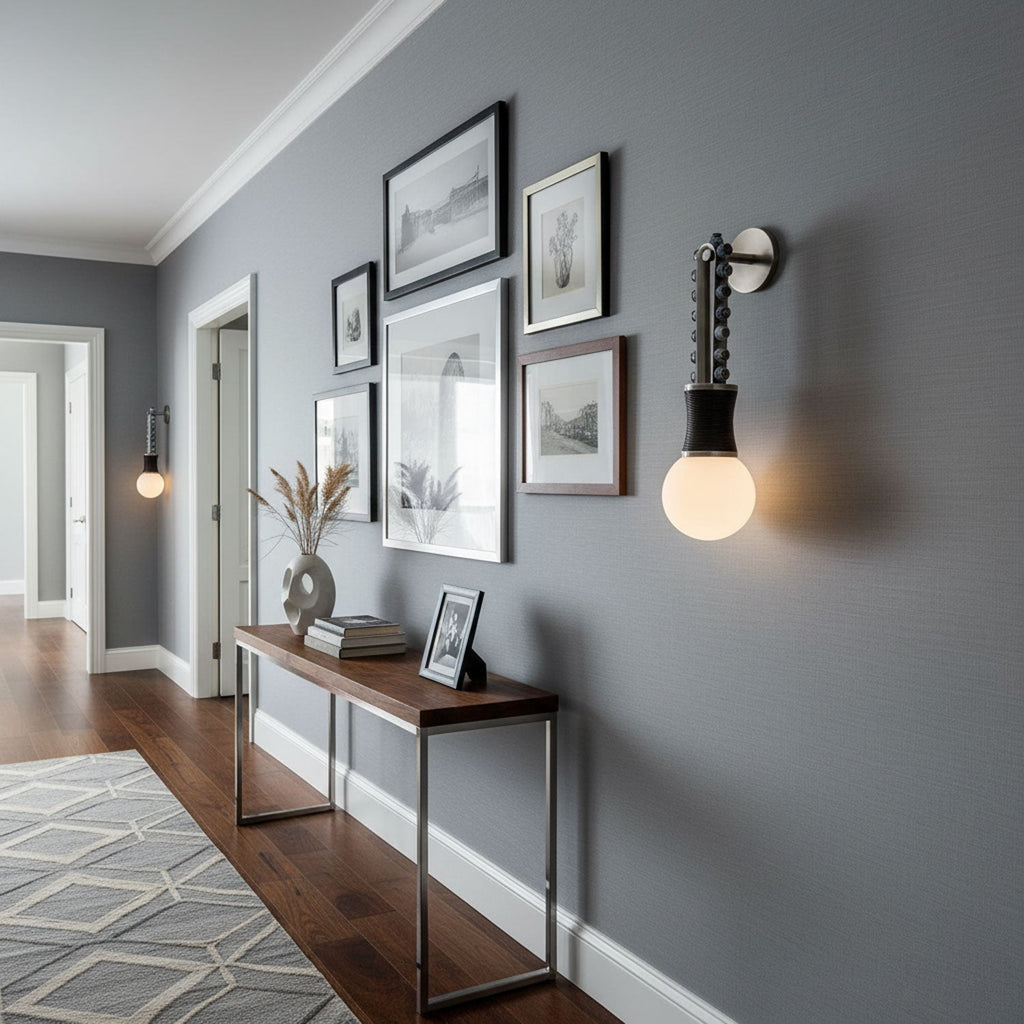 A gallery of framed art lines the hallway wall above a console table, lit by a Clérachic wall sconce.