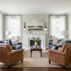 A painting hangs above the fireplace mantel, lit either side by two Clérachic wall sconces in a sage-green living room.