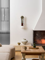 Clérachic wall sconce lit in a living room corner, with a sofa, coffee table and fireplace visible nearby.