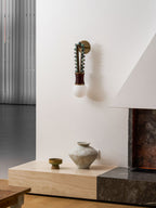 Sage-green beads and a maroon-wrapped base glow on a Clérachic wall sconce near a white fireplace corner.