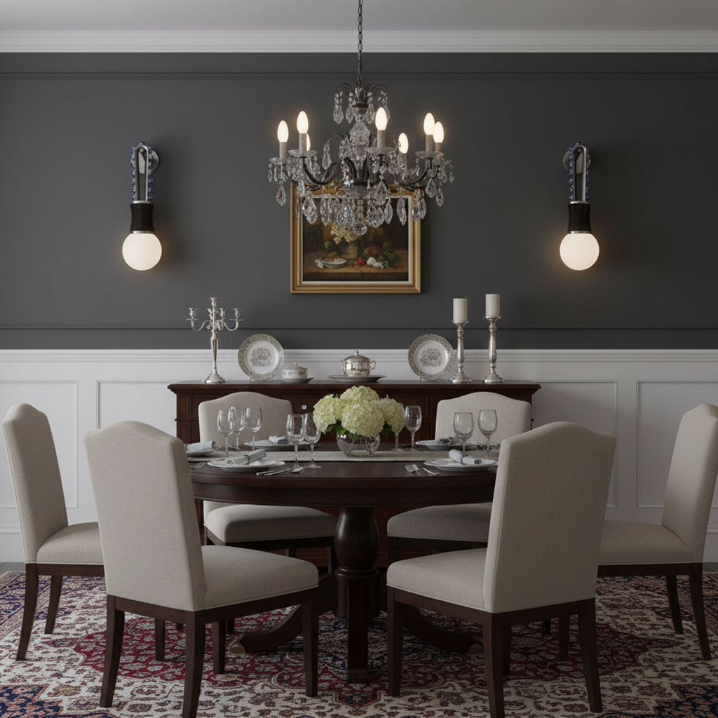 In a dark grey dining room, a crystal chandelier hangs above the table between two lit Clérachic wall sconces.