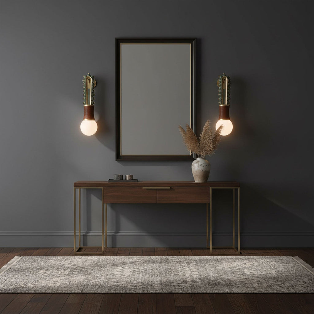 A mirror above a console table sits between two lit Clérachic wall sconces in a dark blue-grey room.