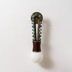 Clérachic wall light mounted on a plain white wall, sage-green stone beads and a maroon-wrapped base shown straight-on.