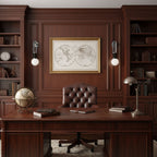 Two Clérachic wall sconces lit either side of a framed map above a leather-topped desk in a dark wood-panelled office.