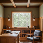 Two Clérachic wall sconces lit either side of a large window in a wood-panelled study with a beamed ceiling.