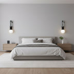 Wood nightstands flank a low platform bed lit either side by two Clérachic wall sconces in a neutral grey bedroom.