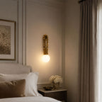 A pillow lies visible on the bed below, lit by a Clérachic wall sconce in the bedroom corner near curtains.