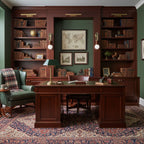 A framed map hangs between two lit Clérachic wall sconces in a green-panelled library office, a tartan armchair below.
