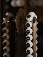 A round wall plate anchors this Clérachic wall sconce, its white marbled stone beads set on a dark bronze frame.