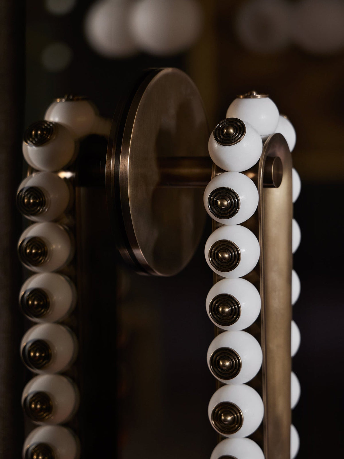 A round wall plate anchors this Clérachic wall sconce, its white marbled stone beads set on a dark bronze frame.