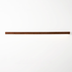Slim wooden wall light with frosted shade glowing warmly