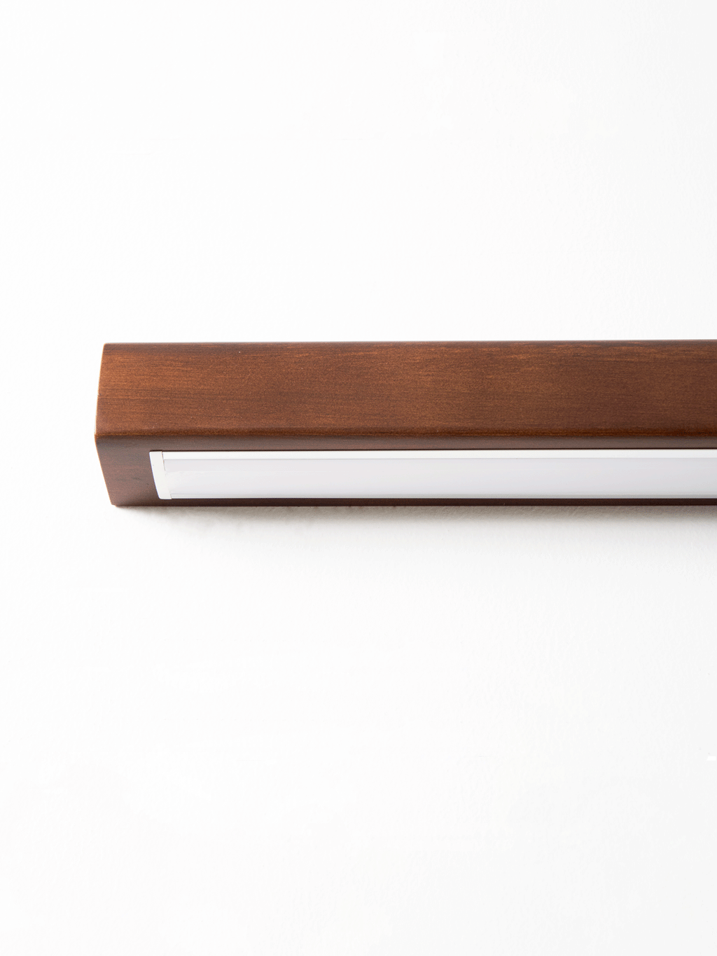 Slim wooden linear wall light glowing softly in a hallway