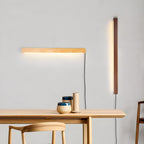 Round wood wall light shown lit in a minimalist room