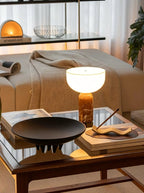 Clérachic's sphere table lamp lit on a wooden coffee table beside a stack of magazines and a black dish.