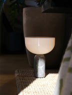 Clérachic's grey marble table lamp glows in a dim, moody room beside a woven rug and a tall dark vase.