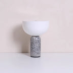 Clérachic's sphere table lamp with a grey marble base, photographed alone against a warm beige backdrop.
