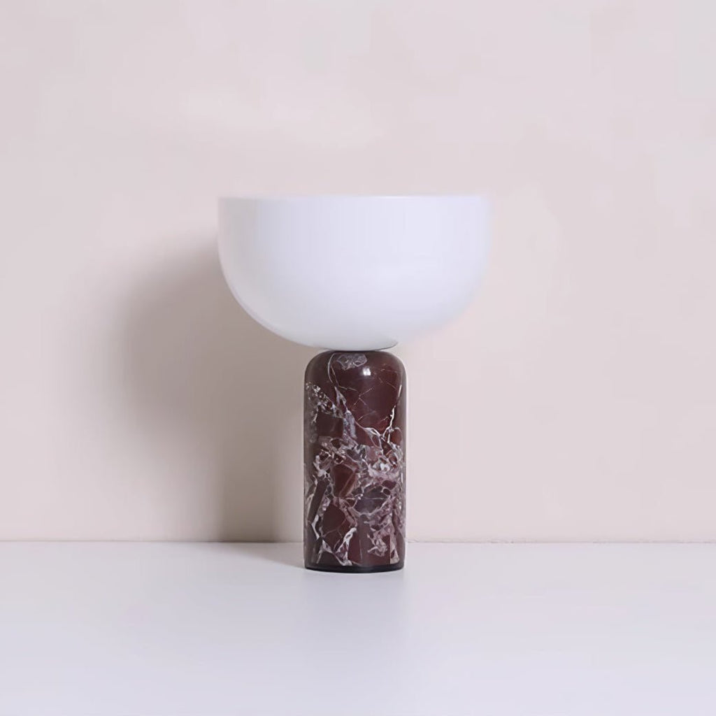 Clérachic's sphere table lamp in dark red marble, photographed against a warm beige studio backdrop.
