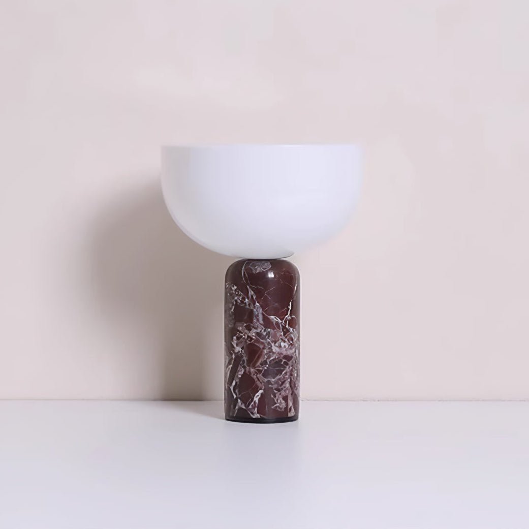 Clérachic's sphere table lamp in dark red marble, photographed against a warm beige studio backdrop.