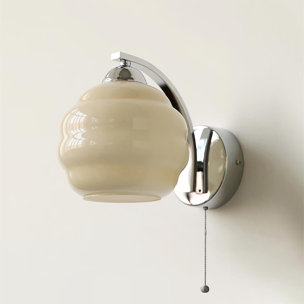 Glass shade wall lamp casting a soft golden glow indoors
