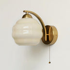 Vintage wall lamp glowing warmly beside a bedside table