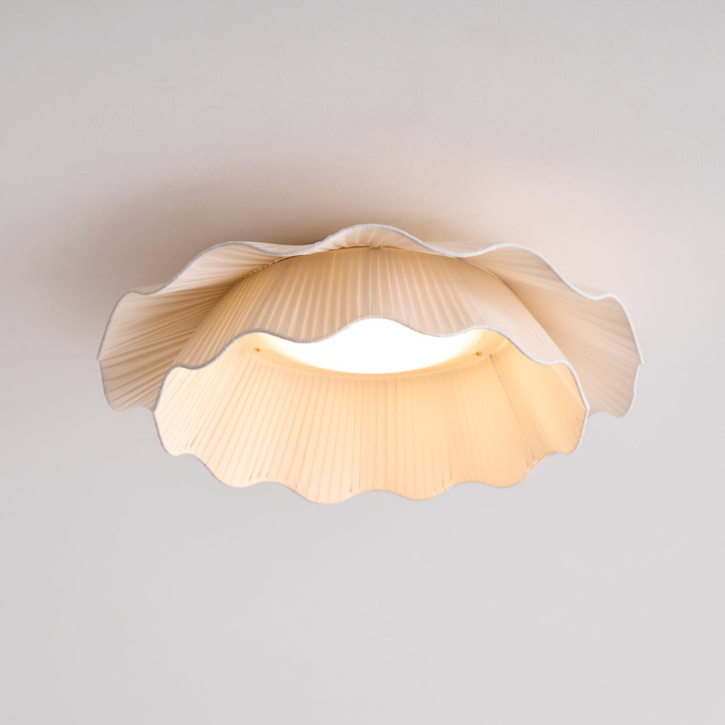 Pleated wave fabric ceiling light lit above an interior space