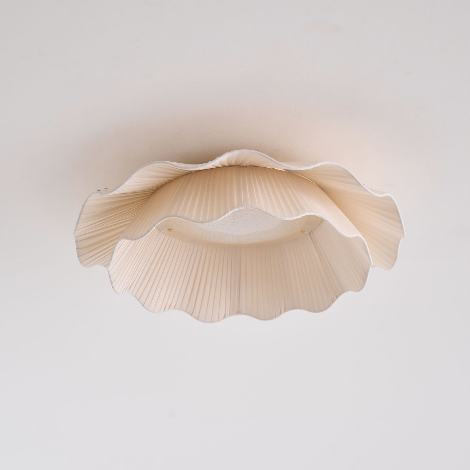 Pleated wave fabric ceiling light glowing in a living area