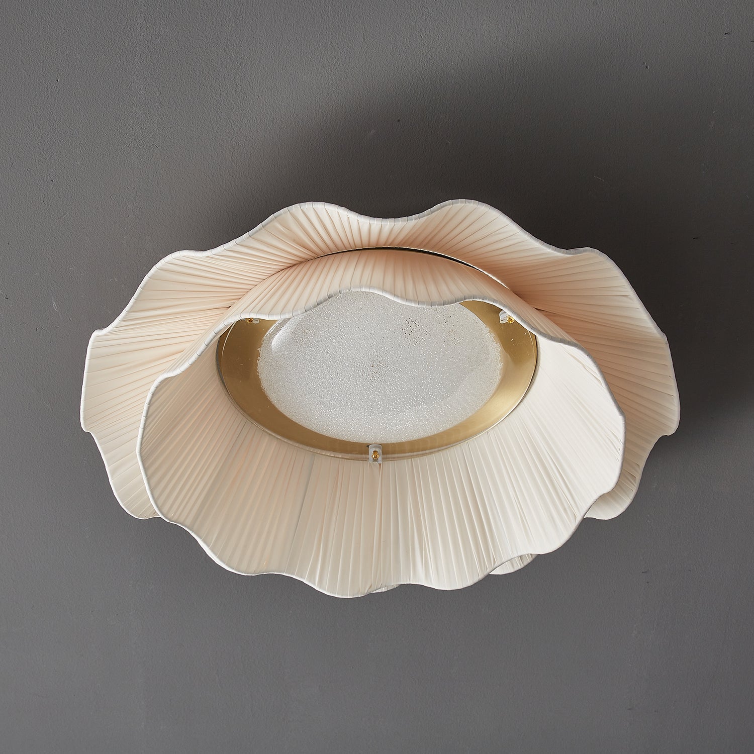 Pleated wave fabric ceiling light glowing warmly indoors