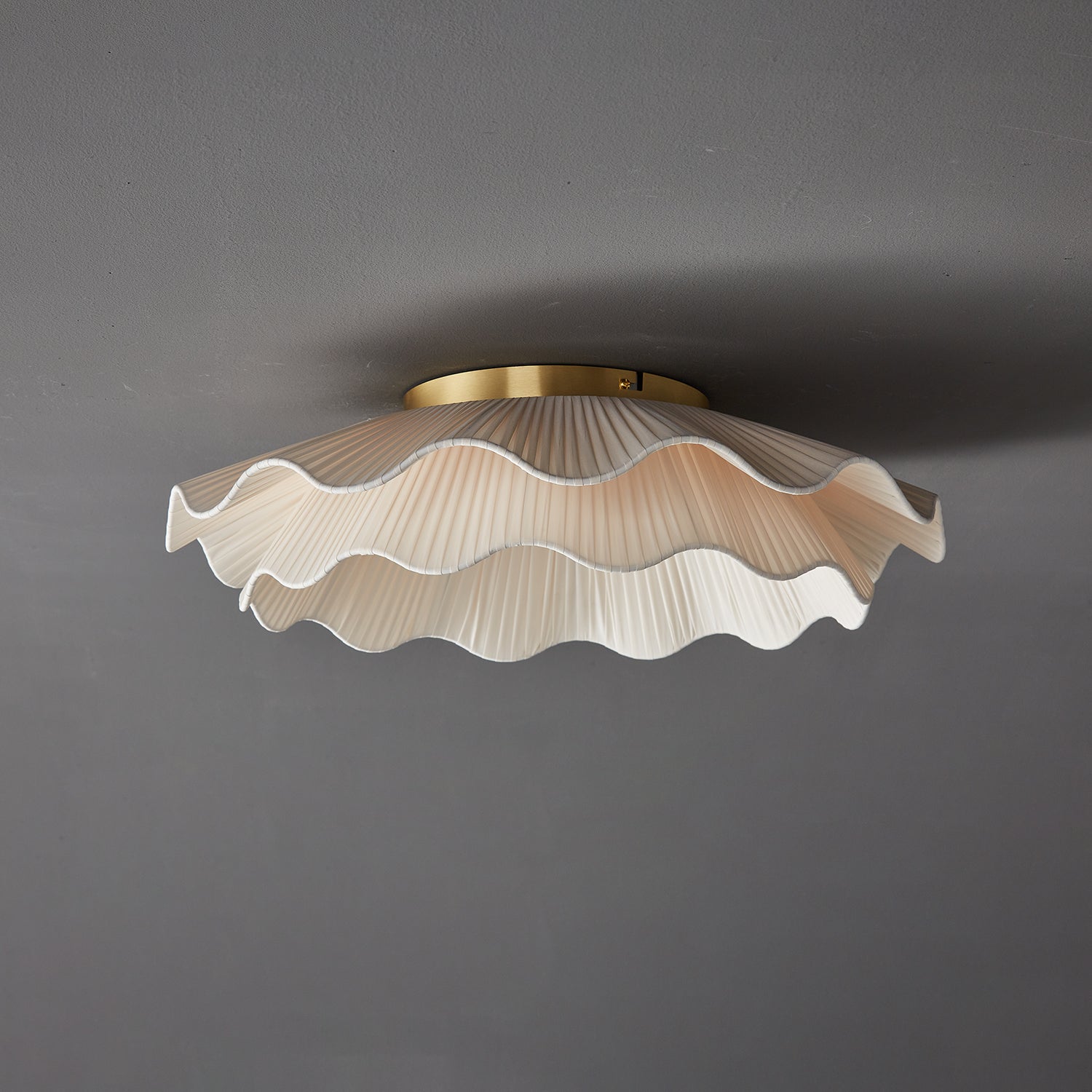 Pleated wave fabric ceiling light shown from below lit
