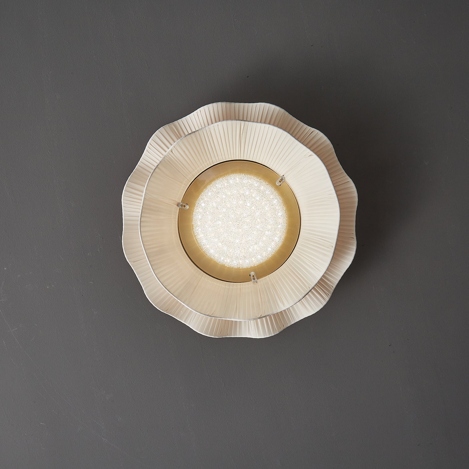 Pleated wave fabric ceiling light glowing in an interior