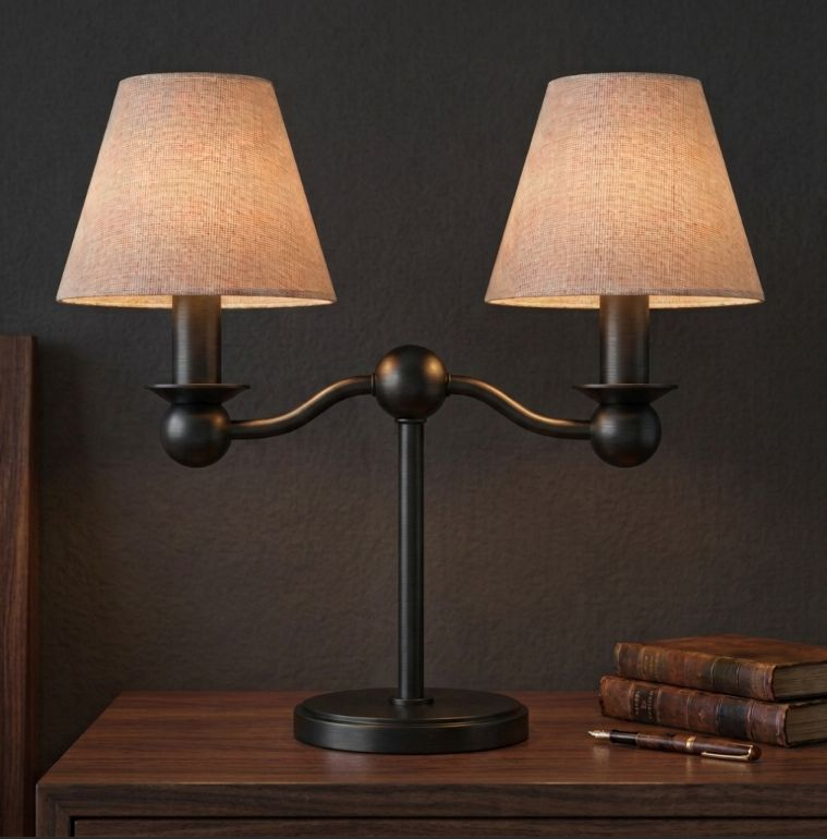 In matte black, this Clérachic table lamp pairs two fabric drum shades on a dark wood nightstand beside stacked books.