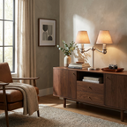 This brushed brass Clérachic table lamp lights a walnut sideboard styled with a vase, books and a leather armchair.