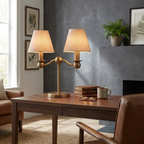 This Clérachic table lamp in brushed brass lights a desk beside a fireplace, with books and a mug nearby.