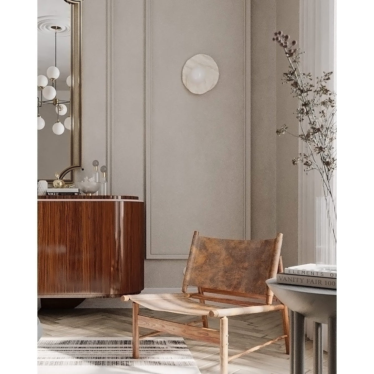 On a panelled wall beside dried branches, a Clérachic wall light hangs near a wood dresser and a leather-strap lounge chair.