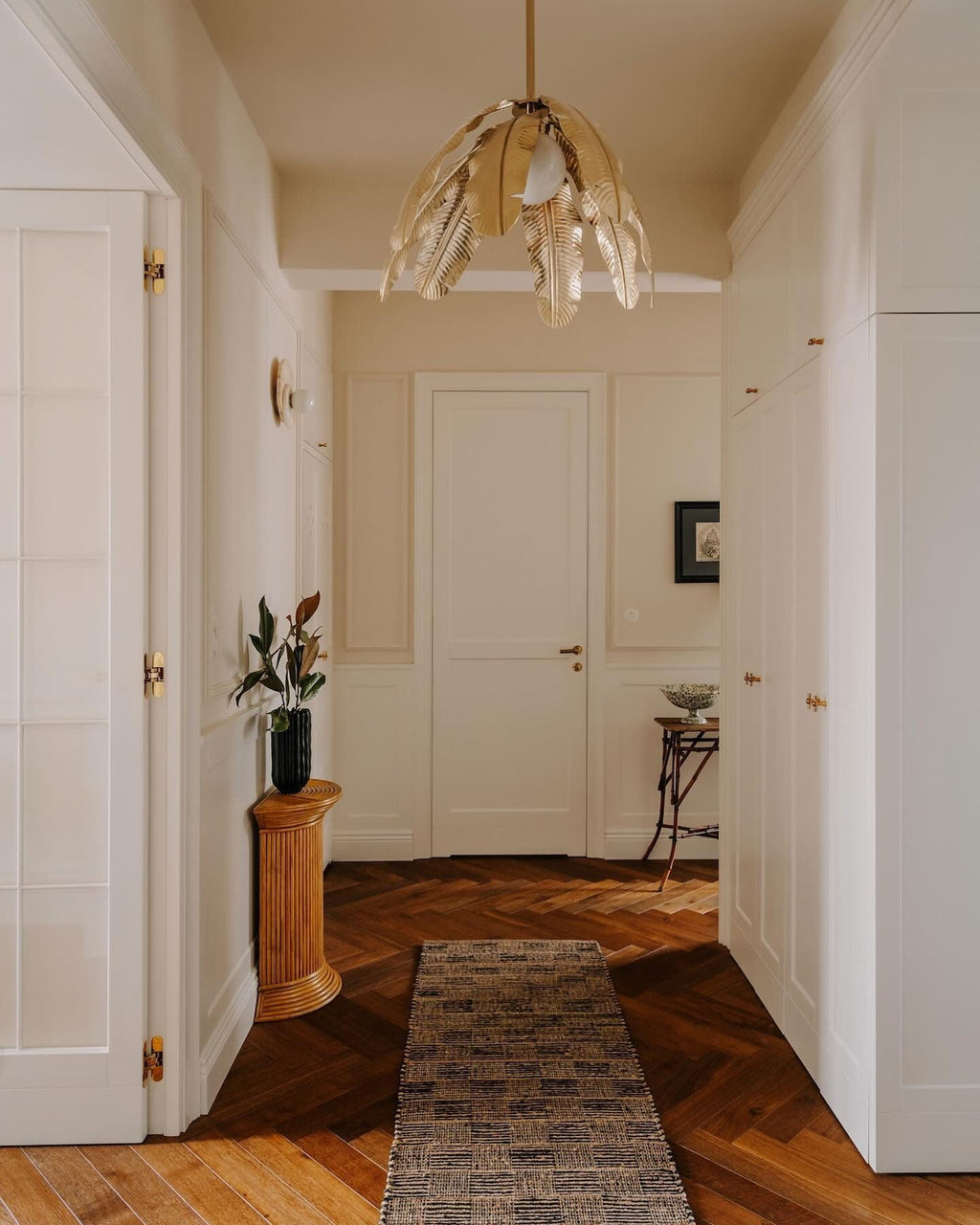 A pendant lights a panelled hallway with a herringbone runner, part of the Clérachic interior collection featuring this wall light.